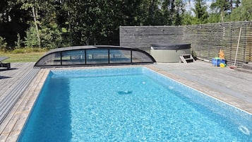 A rectangular swimming pool with a wooden deck surrounding it.