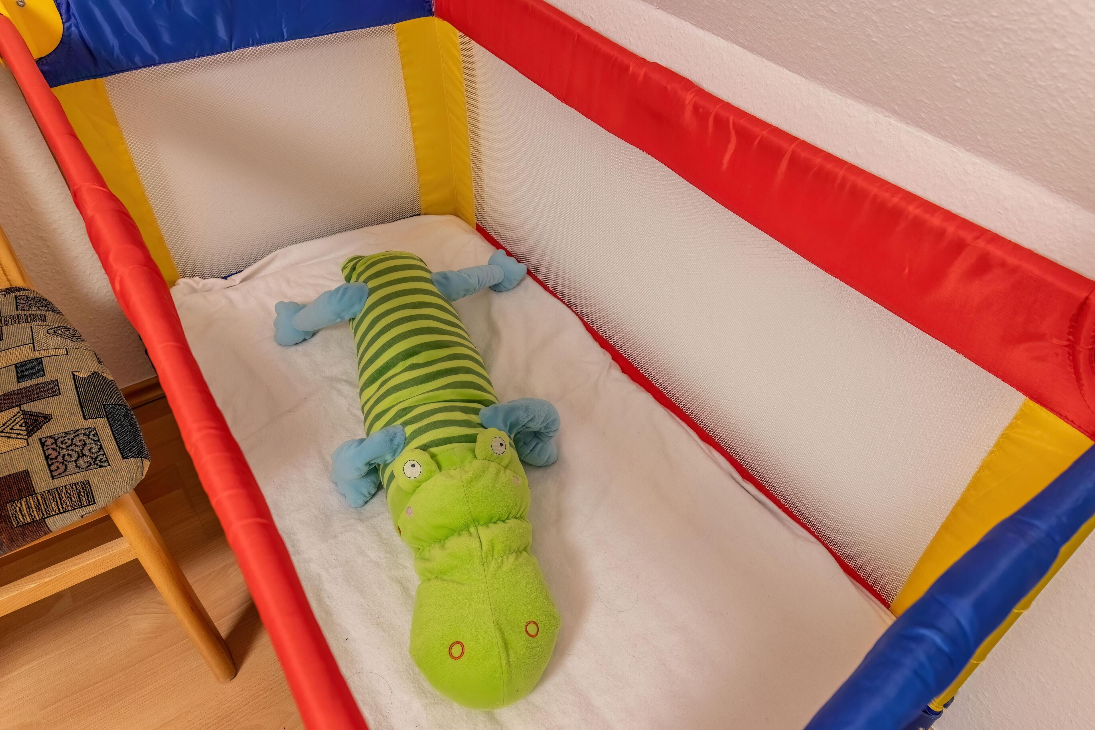 A baby playpen with a green toy inside.