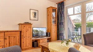 Una habitación acogedora con un escritorio de madera, televisión y vistas al exterior.