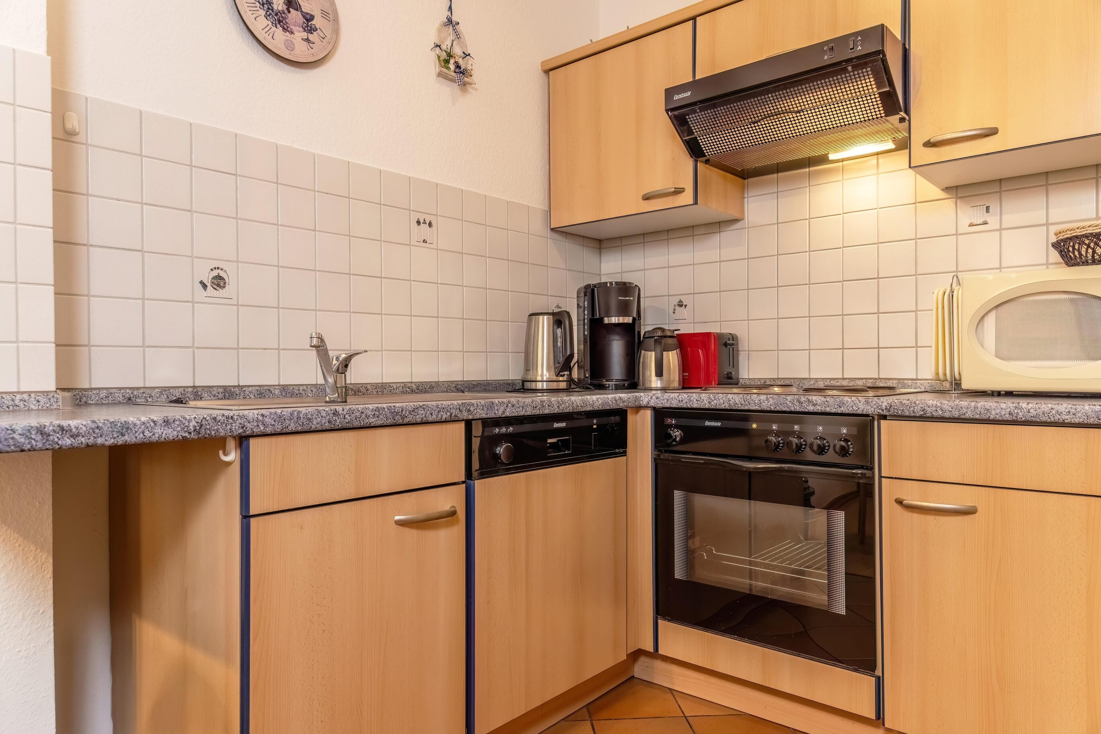 Een keuken met houten kastjes, een vaatwasser, een oven, een koffiezetapparaat en een magnetron.