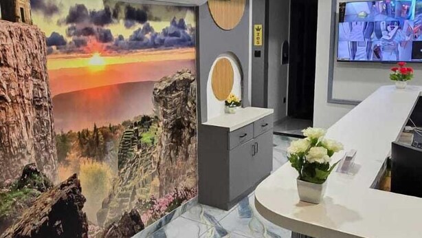 A modern reception area with a marble floor, a mural of a sunset, and a reception desk with a plant. - hotel A-one (Gandhinagar)