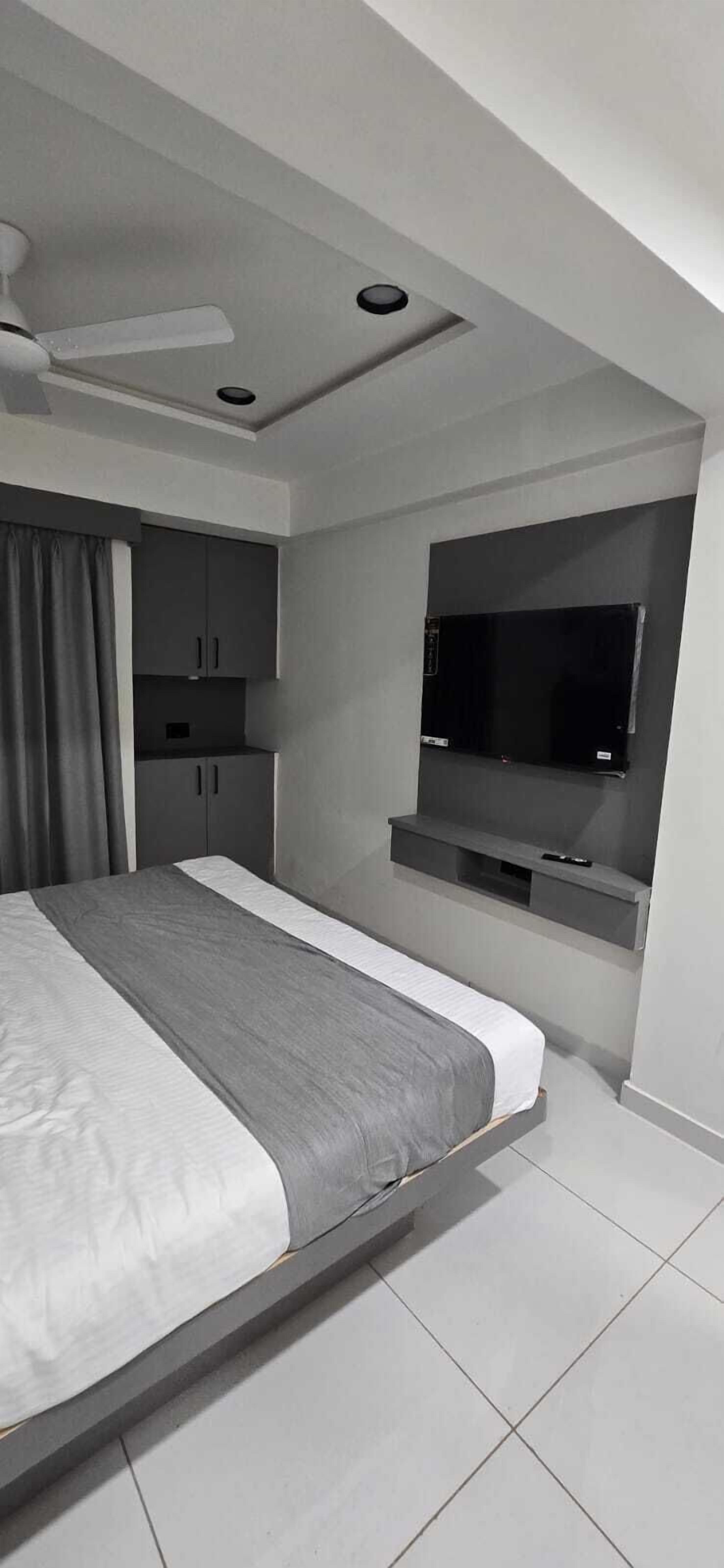 Een moderne slaapkamer met een bed, een plafondventilator, inbouwmeubels, een televisie en een raam.