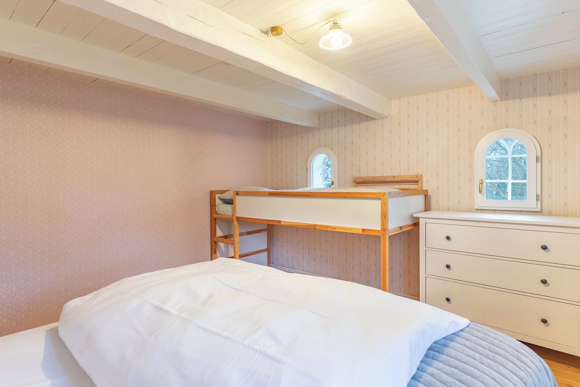 Una camera da letto con un letto a castello, una scrivania, un comò e una finestra.