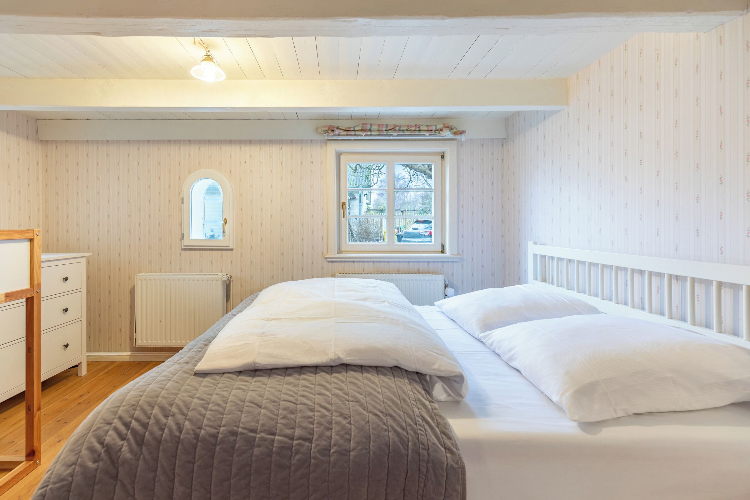 Ein Schlafzimmer mit einem Bett, einem Schminktisch, einem Fenster und einer Heizung.