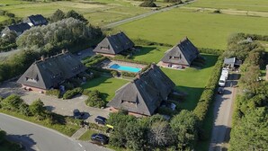 A rural property with thatched-roof cottages, a swimming pool, and a road. - Cozy 3-room vacation apartment on approx. 80 m² for 4 persons. (Wenningstedt-Braderup (Sylt))