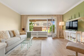 A modern living room with a sofa, glass coffee table, and a television. - Cozy 3-room vacation apartment, approximately 80 m², for 4 people. (Wenningstedt-Braderup (Sylt))
