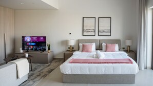 Een moderne hotelkamer met een groot bed, nachtlampjes, een flatscreen televisie en twee ingelijste foto’s aan de muur.