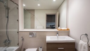 Een moderne badkamer met een douche met glazen wand, een wastafel en een badkamermeubel met spiegel.