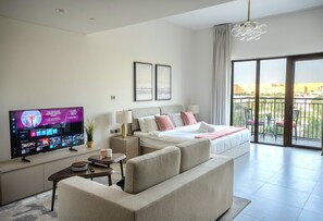 Ein modernes Hotelzimmer mit einem großen Flachbildfernseher, einem bequemen Sofa, einem ordentlich bezogenen Bett und einem Balkon mit Blick.