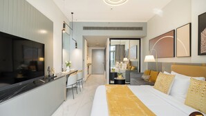 A modern hotel room with a large bed, a dining area, and a view of the hallway. - Vogue| Downtown close to Burj Khalifa | Dubai Mall (Dubai)
