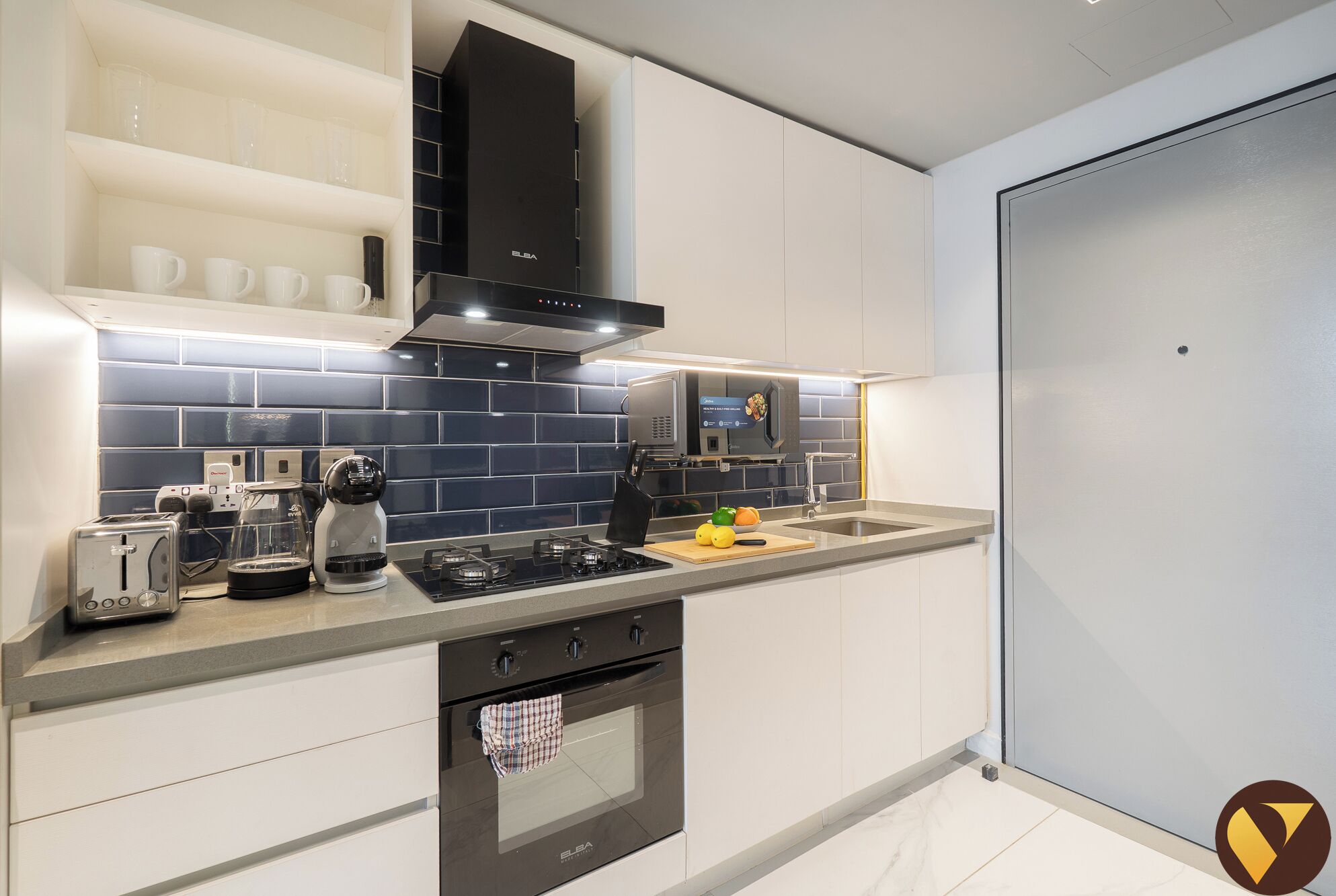A modern kitchen with white cabinets, a black range hood, a built-in microwave, and a gas stove.