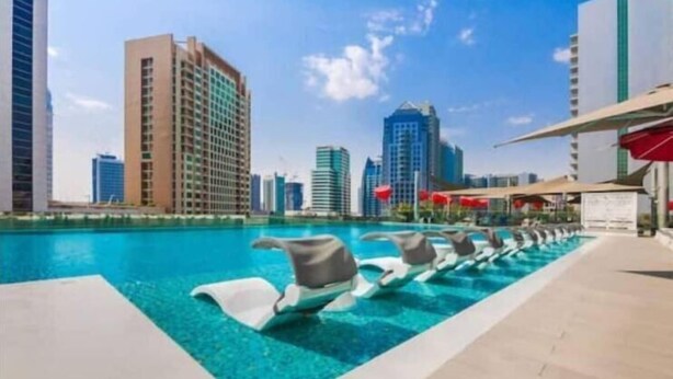 A pool area with lounge chairs and a city skyline in the background. - Vogue| Downtown close to Burj Khalifa | Dubai Mall (Dubai)