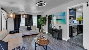 A modern living room with a sofa, a coffee table, and a painting of a beach scene. - Backyard Zen  Retreat with Modern Vibe (Tampa)