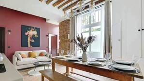 Un comedor con una mesa de madera dispuesta para cuatro personas, una pared de ladrillo y un ventanal grande.