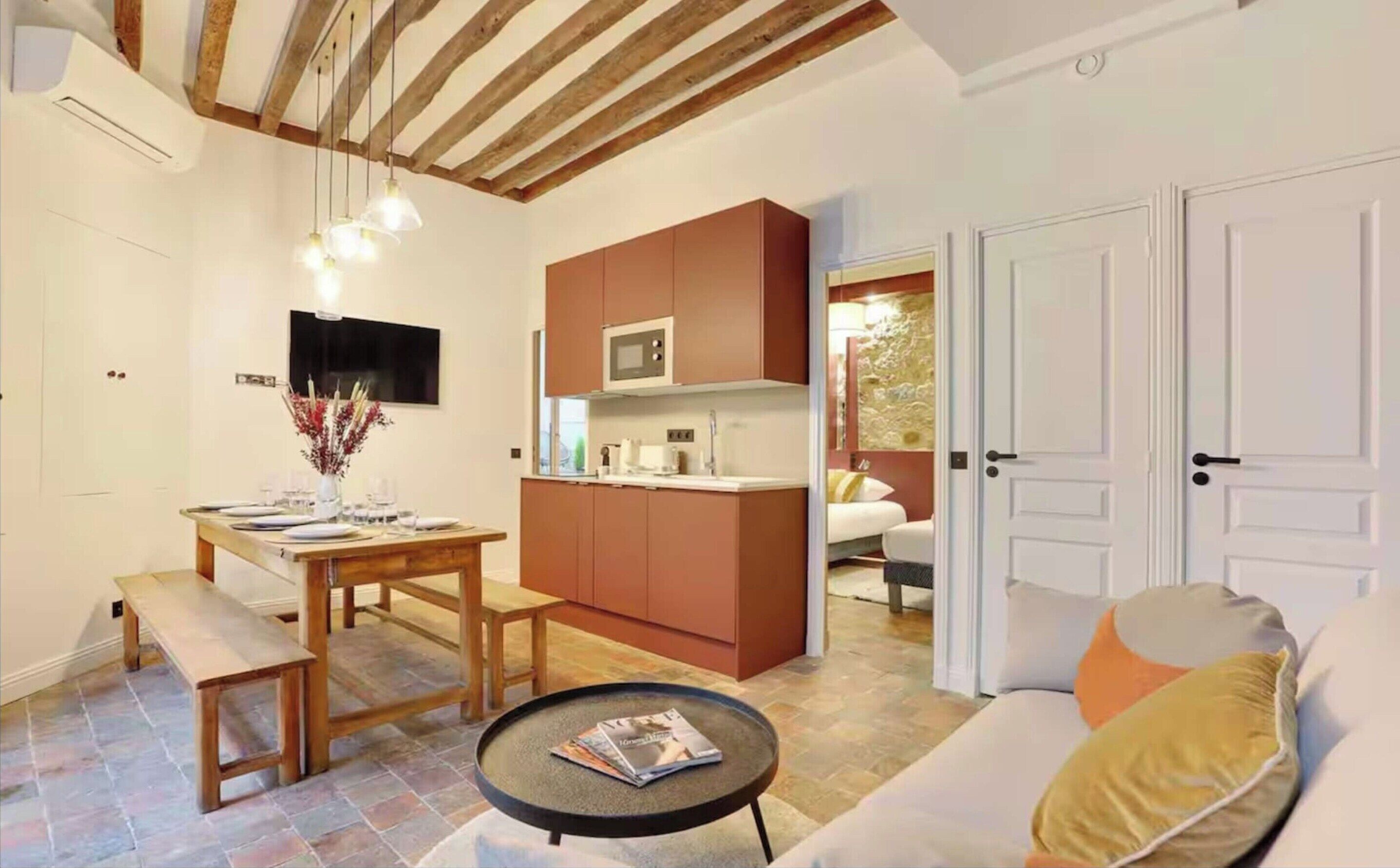 A compact living space with a dining area, kitchenette, and a sofa with cushions.