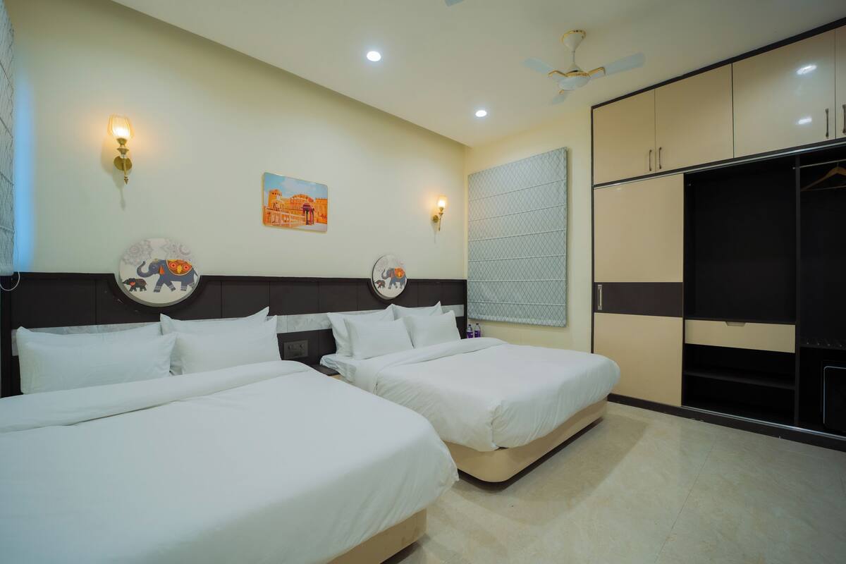 A hotel room with two beds, a wardrobe, and a ceiling fan.