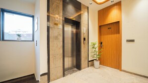 Een lift met een 'LIFT'-bord, een kamerplant en een houten deur.