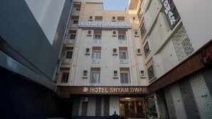 Een meerlaags hotel met een bord waarop 'HOTEL SHYAM DWAR' staat.