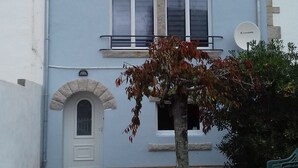 A two-story building with a flat roof, a small front garden, and a satellite dish. - The beach at the end of the street (Treffiagat)