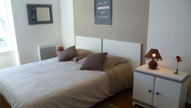 A bedroom with a bed, two nightstands, a mirror, a wall clock, and a motivational quote. - The beach at the end of the street (Treffiagat)