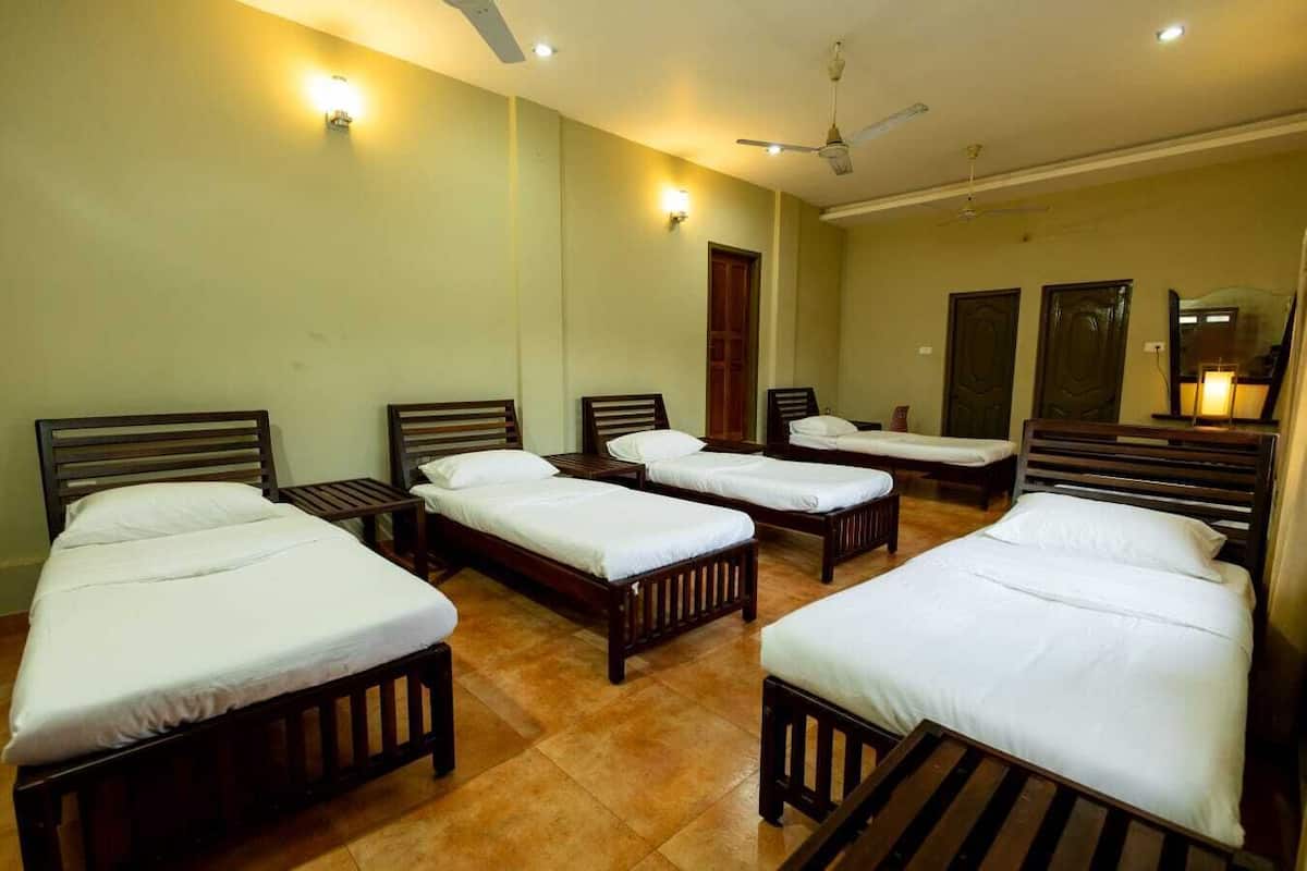 A hotel room with four single beds, wooden headboards, and a tiled floor.
