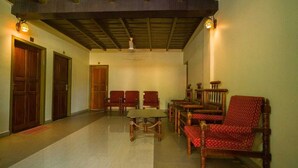 Un pasillo con puertas de madera, una mesa de madera y sillas tapizadas de rojo.