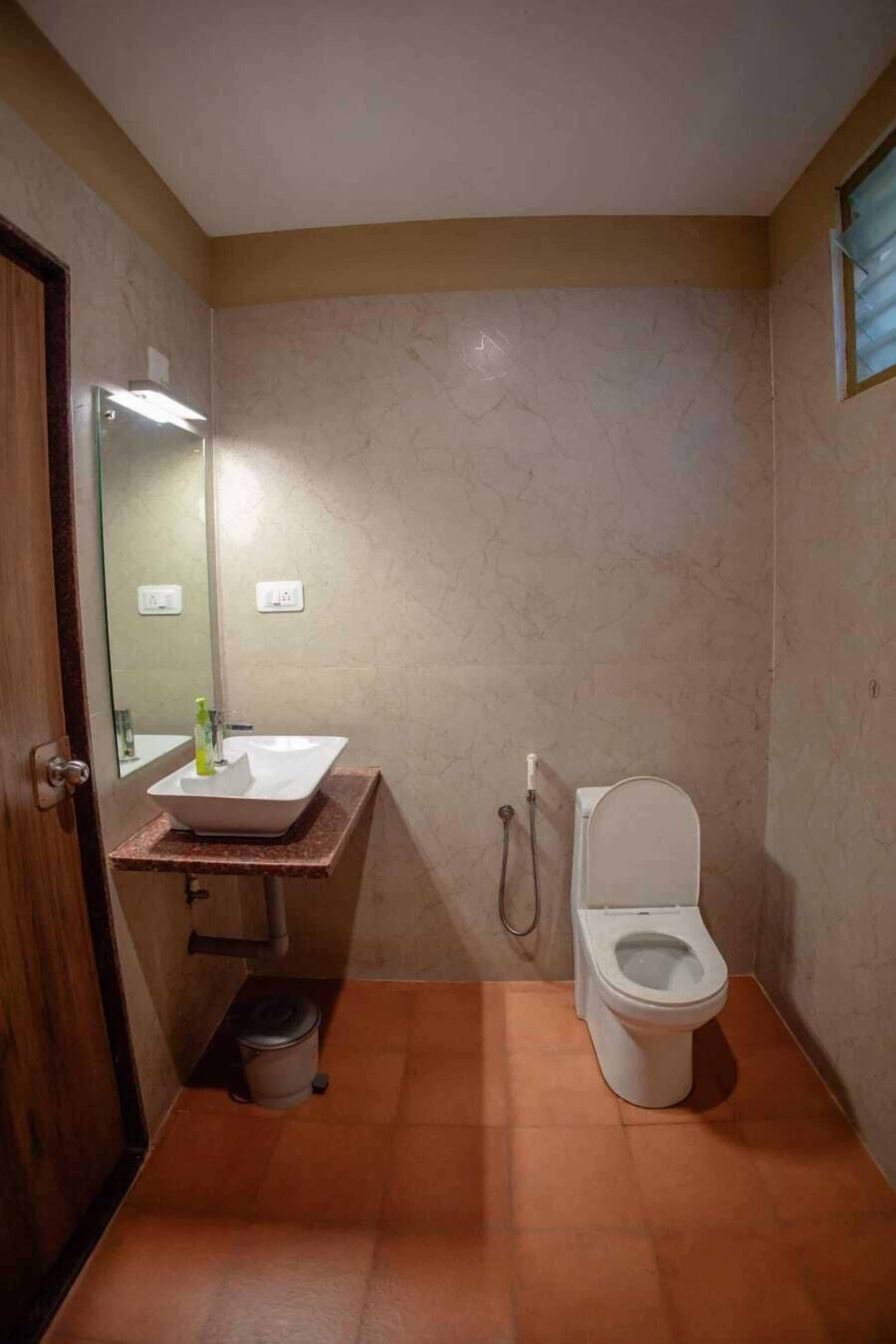 A small bathroom with a white sink, mirror, and toilet.