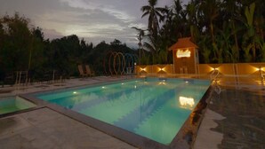 Una piscina con sillas de descanso y un pequeño edificio con la leyenda 'Eldorado University Hotel'.