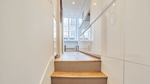 A modern staircase with wooden steps leading to a bright room with large windows. - Charming Studio - Louvre & Palais Royal (Paris)