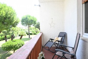 Un balcon avec deux fauteuils de jardin, une décoration en forme d’étoile et une vue sur un jardin agrémenté d’arbres et d’arbustes.