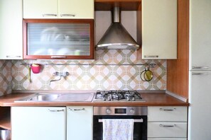 Une cuisine équipée d’une cuisinière à gaz, d’un four et d’un évier en acier inoxydable.