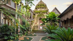 A traditional Balinese courtyard with stone architecture, a central shrine, and lush tropical plants. - Govala Usada Ubud Villa (Tegallalang)