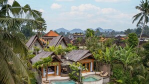 A tropical resort with multiple bungalow-style buildings surrounded by lush greenery and a pool area. - Govala Usada Ubud Villa (Tegallalang)