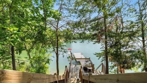 A wooden deck leading to a lake with a gazebo.