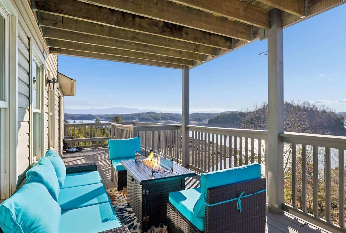 A covered outdoor seating area with a fire feature, overlooking a scenic landscape.