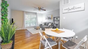 Ein modernes Wohnzimmer mit Esstisch, grauem Sofa und Deckenventilator.