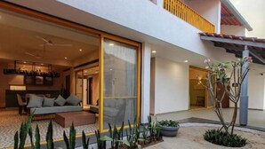 A modern two-story house with a spacious patio area, a dining area, and a living room with a sofa and a coffee table. - Double Room #1 (Igatpuri)