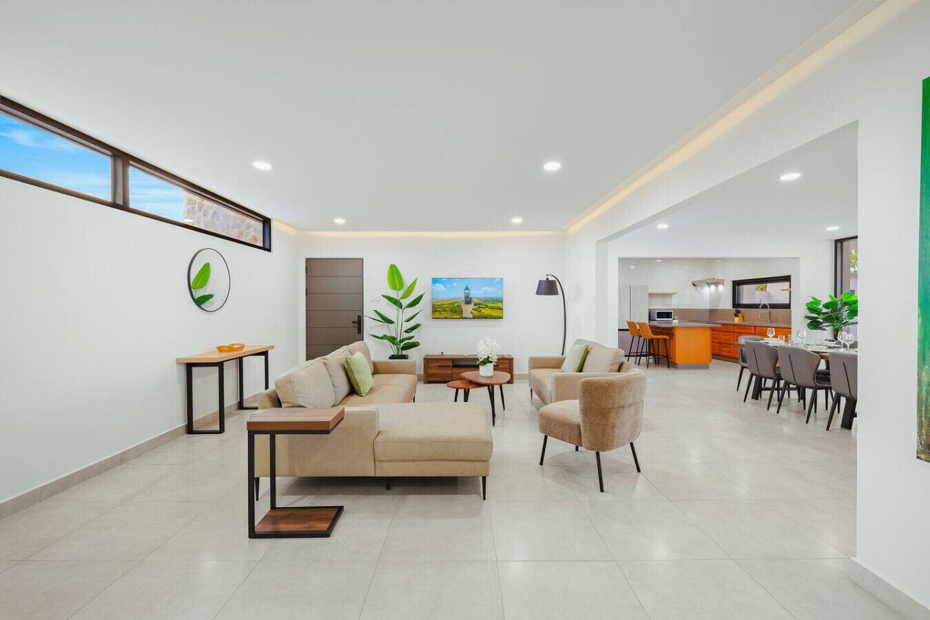 Una sala de estar moderna con un sofá, sillones y un comedor con mesa y sillas.