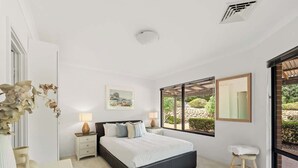 A modern bedroom with a large bed, bedside tables, a mirror, and a view of greenery. - Sailors Hill Retreat—Bushland Living by the Coast (Naturaliste)