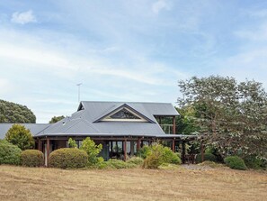 A two-story house with a gabled roof, surrounded by a well-maintained garden and a clear sky. - Sailors Hill Retreat—Bushland Living by the Coast (Naturaliste)