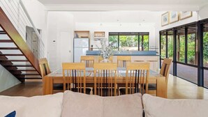 A modern interior with a dining area, kitchen, and large windows. - Sailors Hill Retreat—Bushland Living by the Coast (Naturaliste)