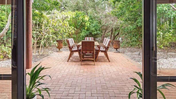 A covered patio with a brick floor, wooden table and chairs, and potted plants. - Sailors Hill Retreat—Bushland Living by the Coast (Naturaliste)