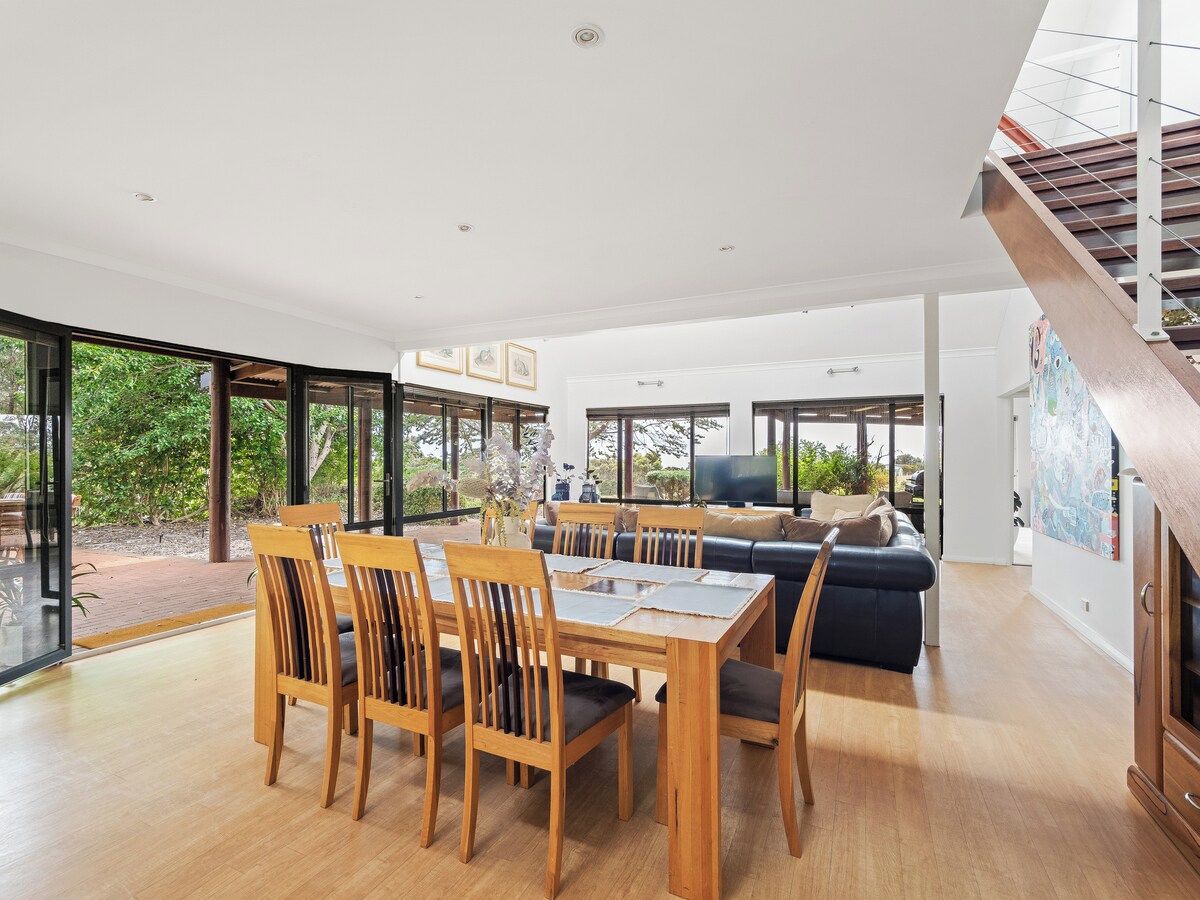 A spacious living area with a wooden dining table and chairs, a sofa, and a staircase.
