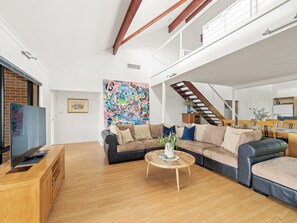 A modern living room with a sectional sofa, a coffee table, and a TV on a wooden stand. - Sailors Hill Retreat—Bushland Living by the Coast (Naturaliste)