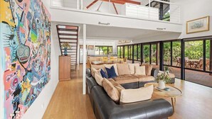 A spacious living area with a large sofa, a dining table, and a kitchen in the background. - Sailors Hill Retreat—Bushland Living by the Coast (Naturaliste)
