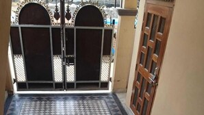 A tiled balcony with a checkered pattern, a metal gate, and a wooden door. - Shri Hari Sadan (Jhusi)