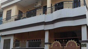 A two-story residential building with a white facade, a balcony on the upper floor, and a large ornate gate at the entrance. - Shri Hari Sadan (Jhusi)