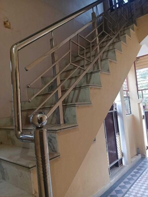 A staircase with metal handrails and a marble-like floor. - Shri Hari Sadan (Jhusi)