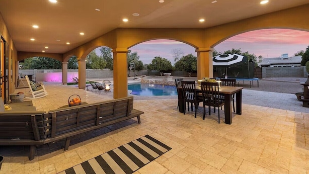 Une terrasse extérieure dotée d’une piscine, de coins salon et d’une partie abritée avec des tables et des chaises.