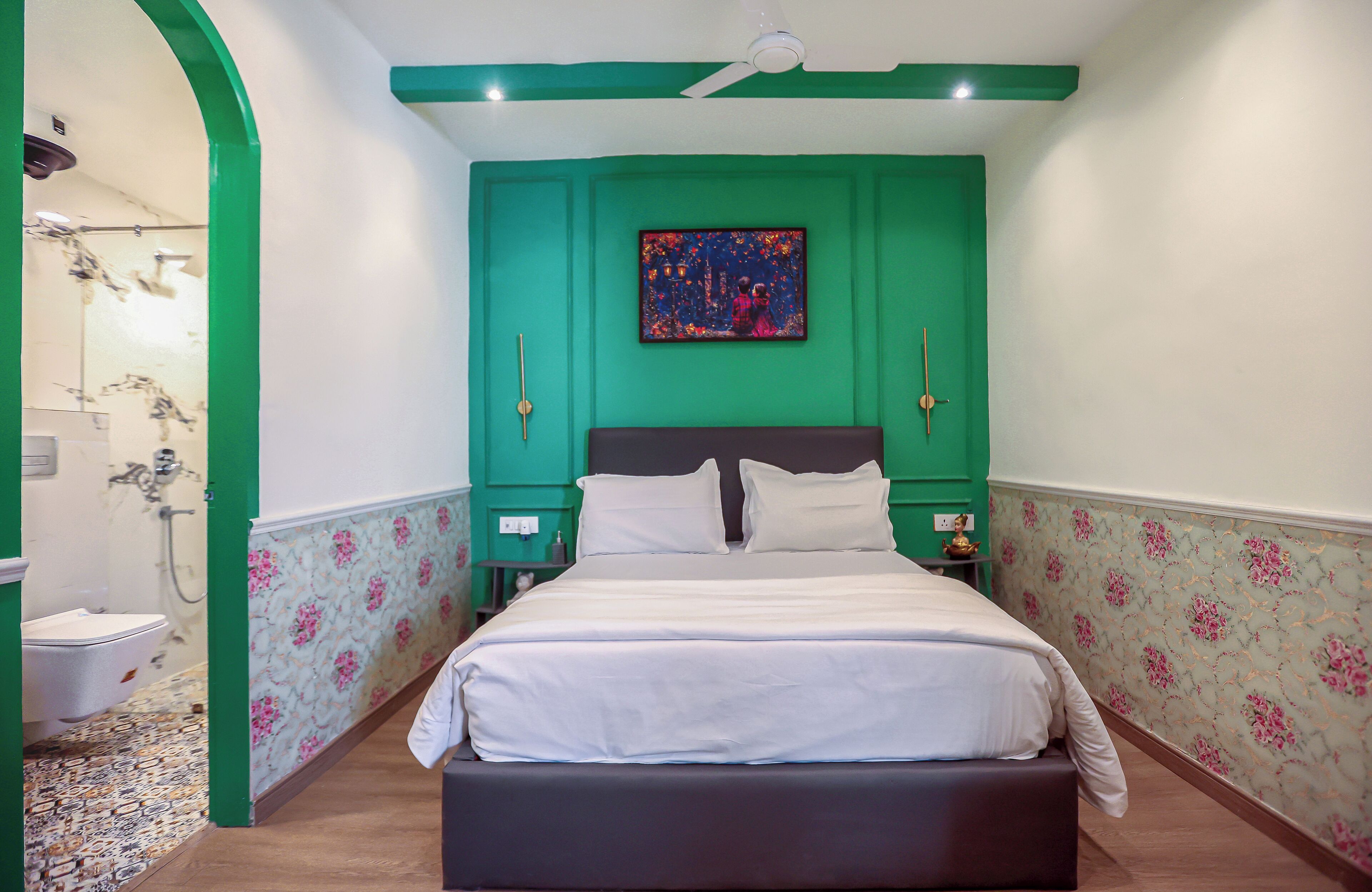 Un dormitorio con cama, paredes verdes, un cuadro y una mesita de noche.